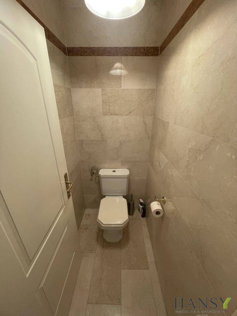Kleines Gäste-WC mit hellen Fliesen an Wänden und Boden.