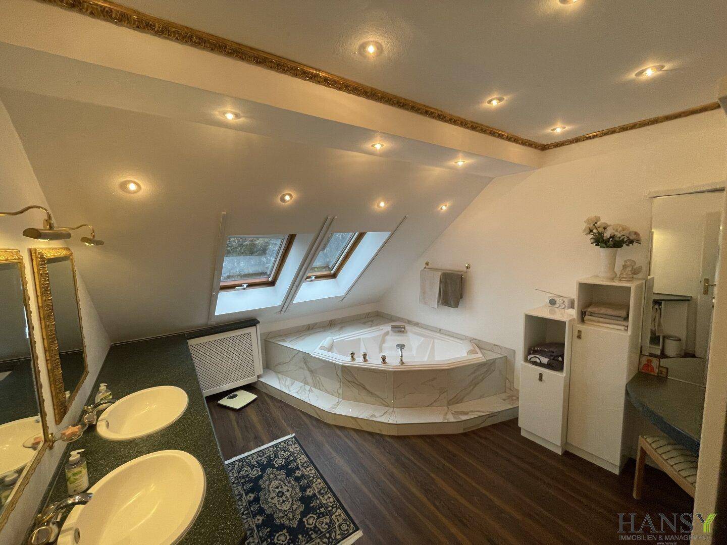 Geräumiges Badezimmer im Dachgeschoss mit Eck-Whirlpool, Doppelwaschbecken und Dachfenstern.