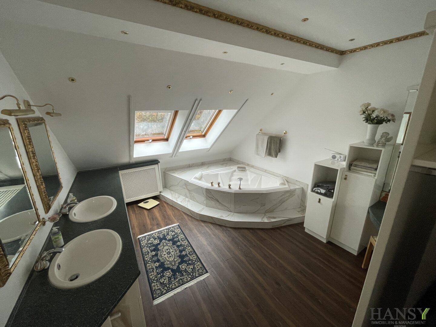 Luxuriöses Badezimmer mit Eck-Whirlpool, Doppelwaschbecken und Dachfenstern für viel Licht.