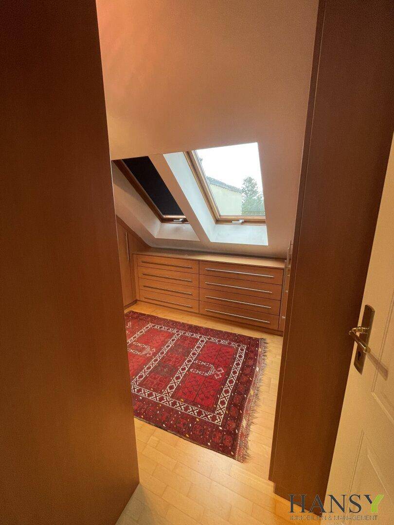 Eingangsbereich zu einem Dachgeschossraum mit Holzschränken und Dachfenstern.