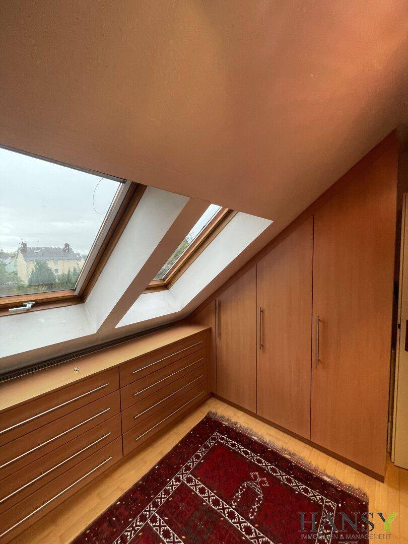 Dachgeschossraum mit maßgefertigten Holzschränken, Schubladen und Dachfenstern.
