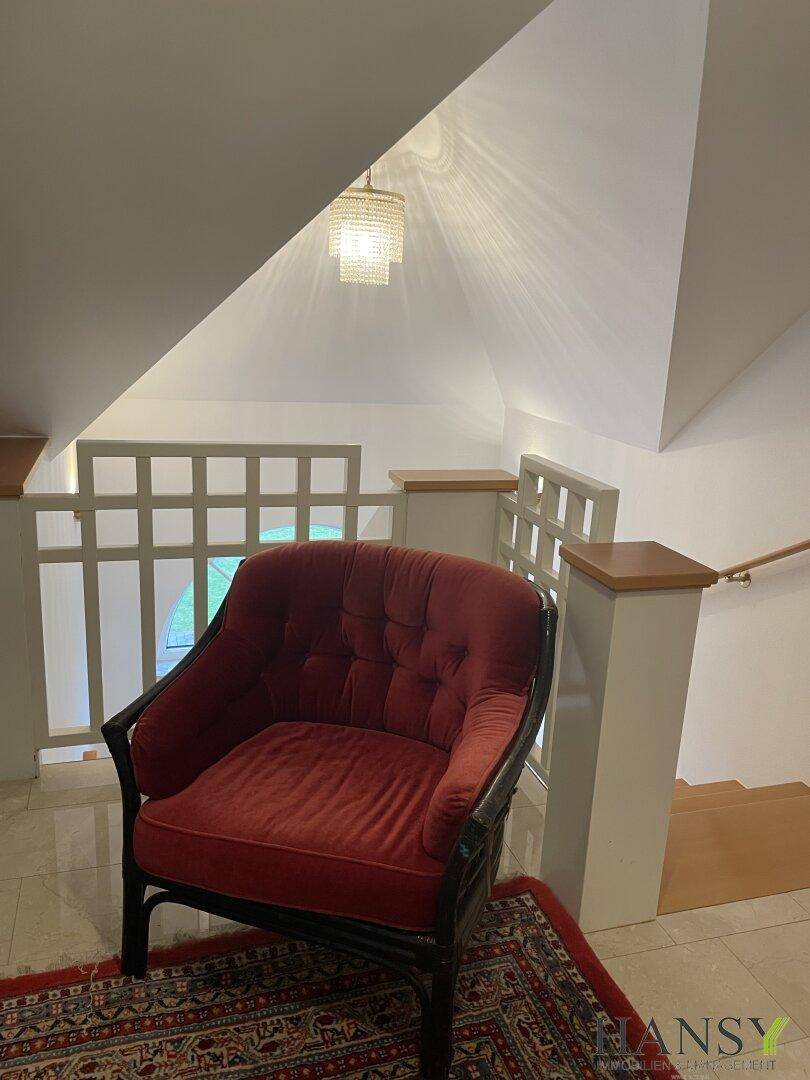 Gemütlicher Treppenabsatz mit rotem Sessel und Blick auf die untere Etage.