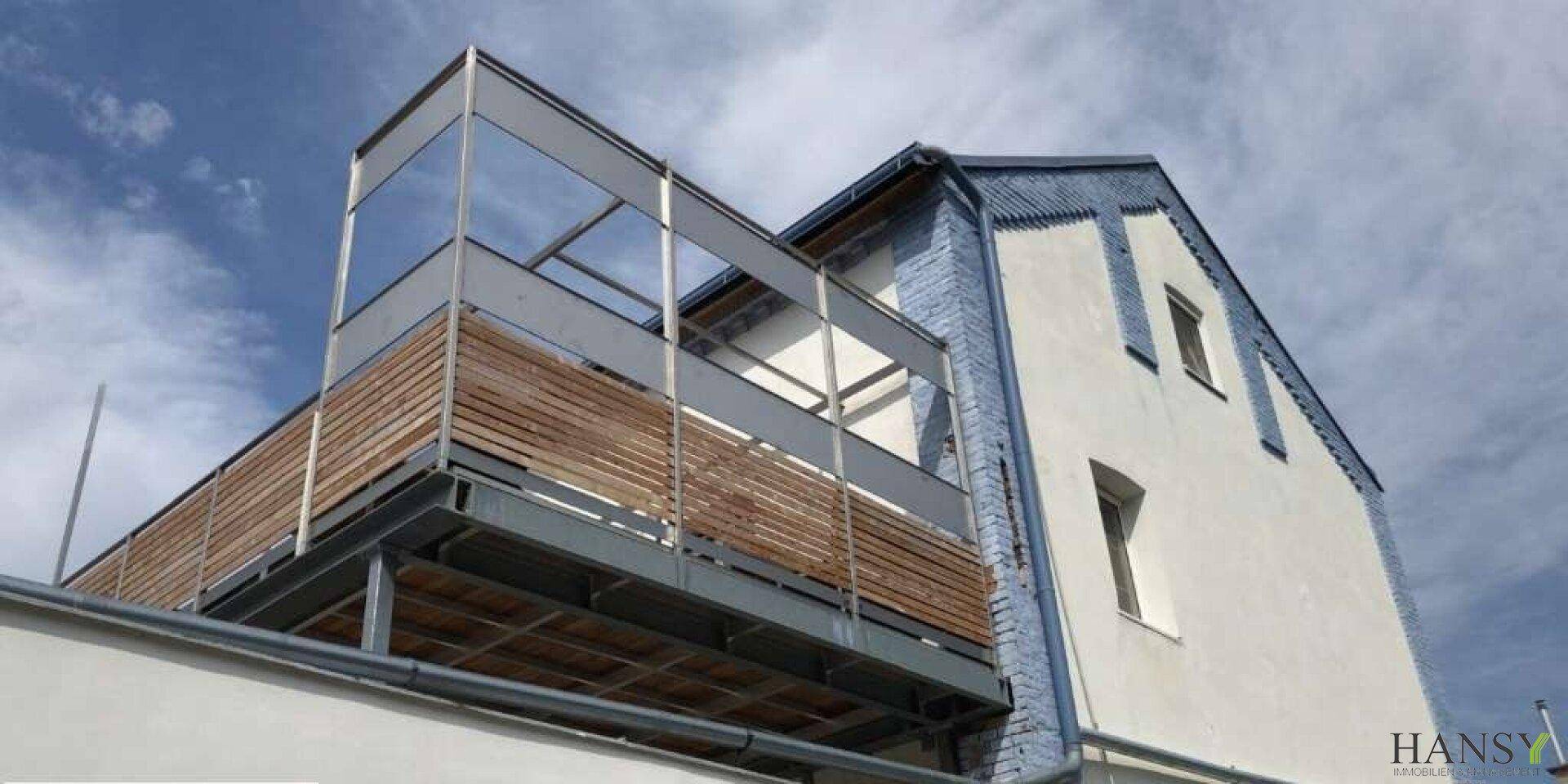 Großer, moderner Balkon mit Holzverkleidung an der Fassade eines Altbaus.