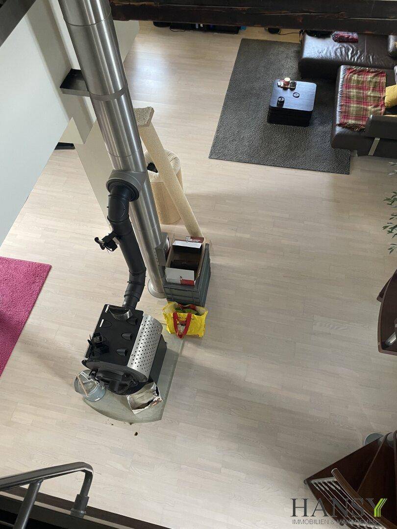 Vogelperspektive auf den Kaminofen und den offenen Wohnbereich mit Laminatboden.