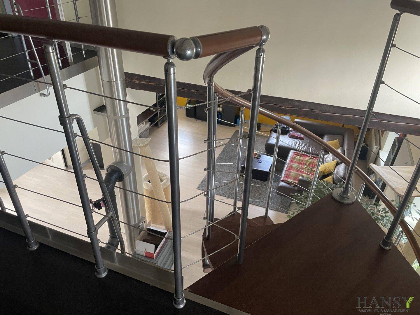 Blick von der oberen Etage auf den offenen Wohnbereich mit Wendeltreppe.