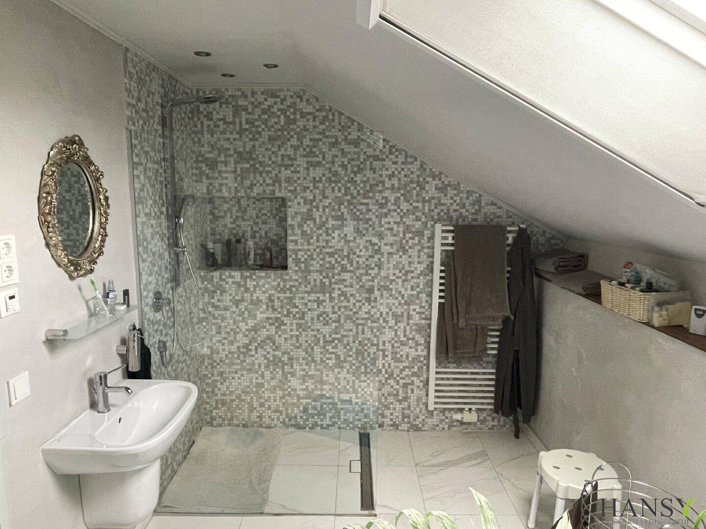 Duschbereich im modernen Badezimmer mit Mosaikfliesen und beheiztem Handtuchhalter.