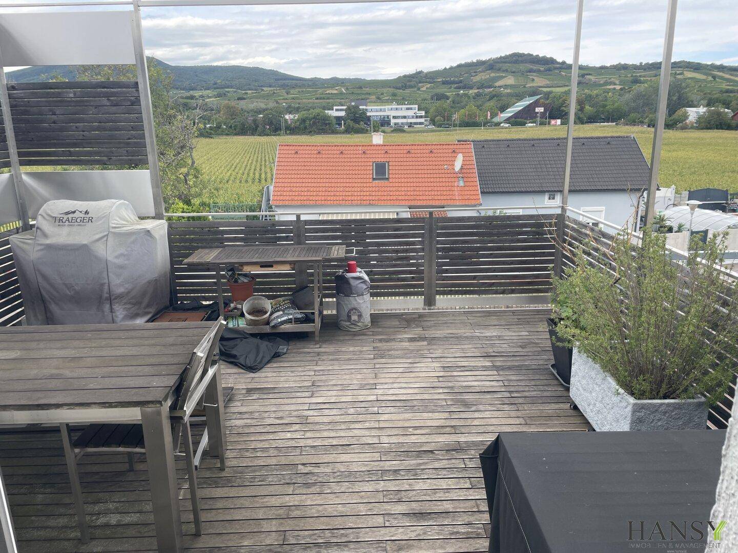 Geräumige Holzterrasse mit Essbereich im Freien und weitem Blick auf die Landschaft.