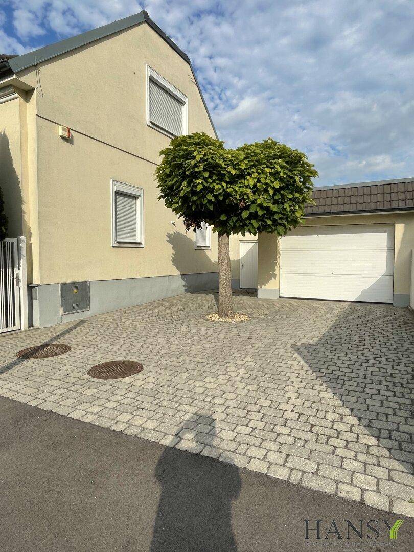 Weitläufige gepflasterte Einfahrt mit Garage und Hausfassade.