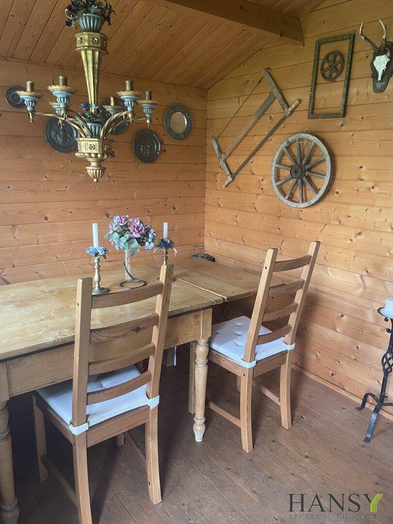 Rustikales Esszimmer im Gartenhaus mit Holzwänden und traditioneller Dekoration.