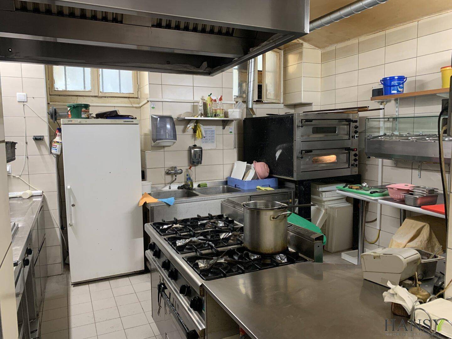 Professionelle Gastronomieküche mit Edelstahlflächen, Gasherd und Backöfen für den Betrieb.