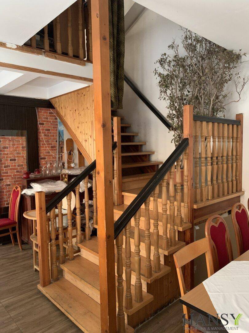 Rustikale Holztreppe im Essbereich mit Ziegelwandakzent und weiteren Sitzgelegenheiten.