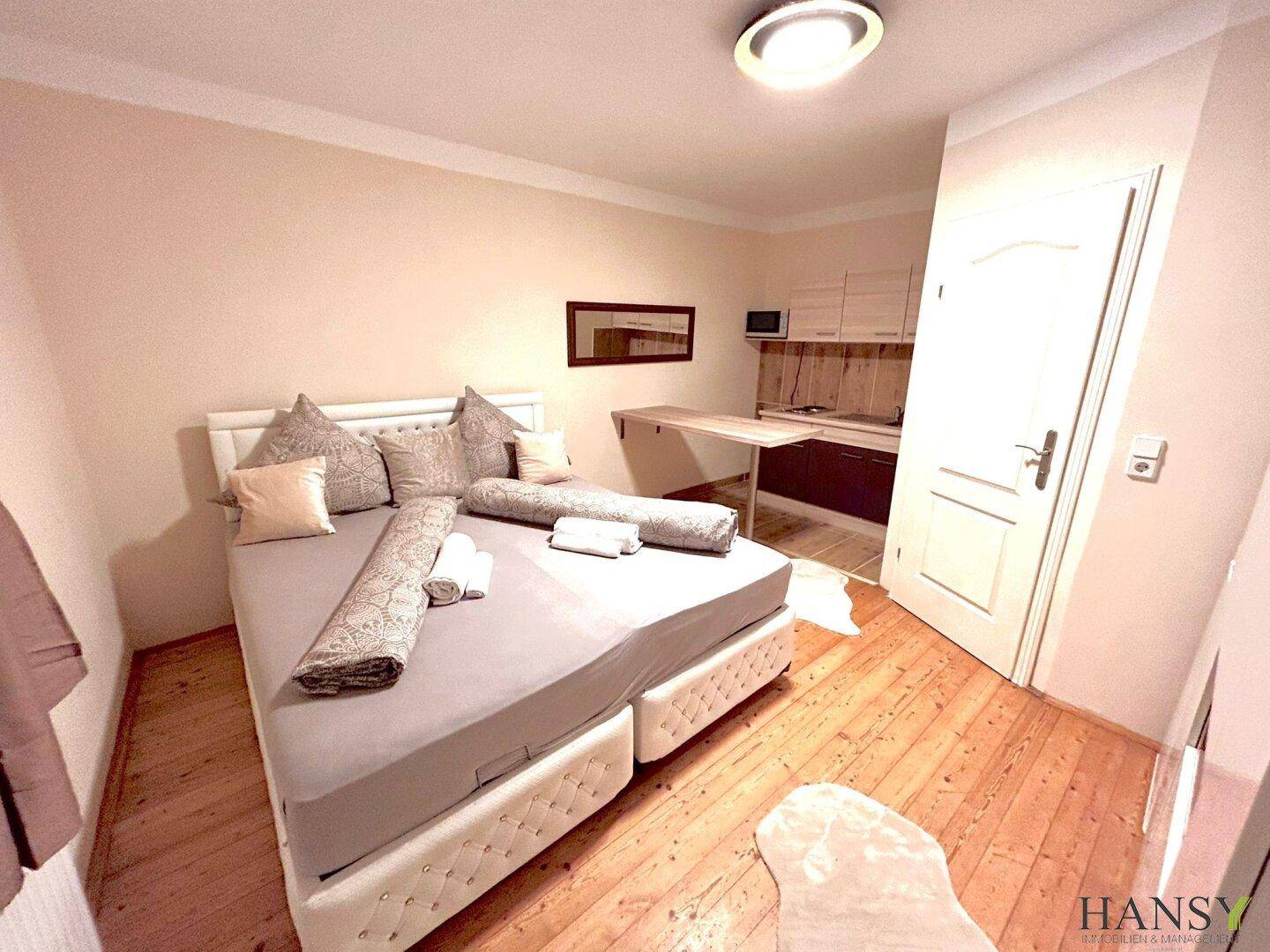 Gemütliches Schlafzimmer mit Doppelbett, Holzboden und integriertem Schreibtischbereich.