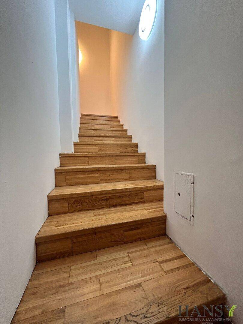 Helle Treppe mit Holzstufen, die in die obere Etage führt.