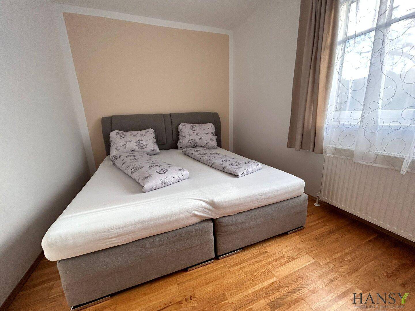 Schlafzimmer mit zwei Einzelbetten, die zu einem Doppelbett zusammengestellt sind, und Holzboden.