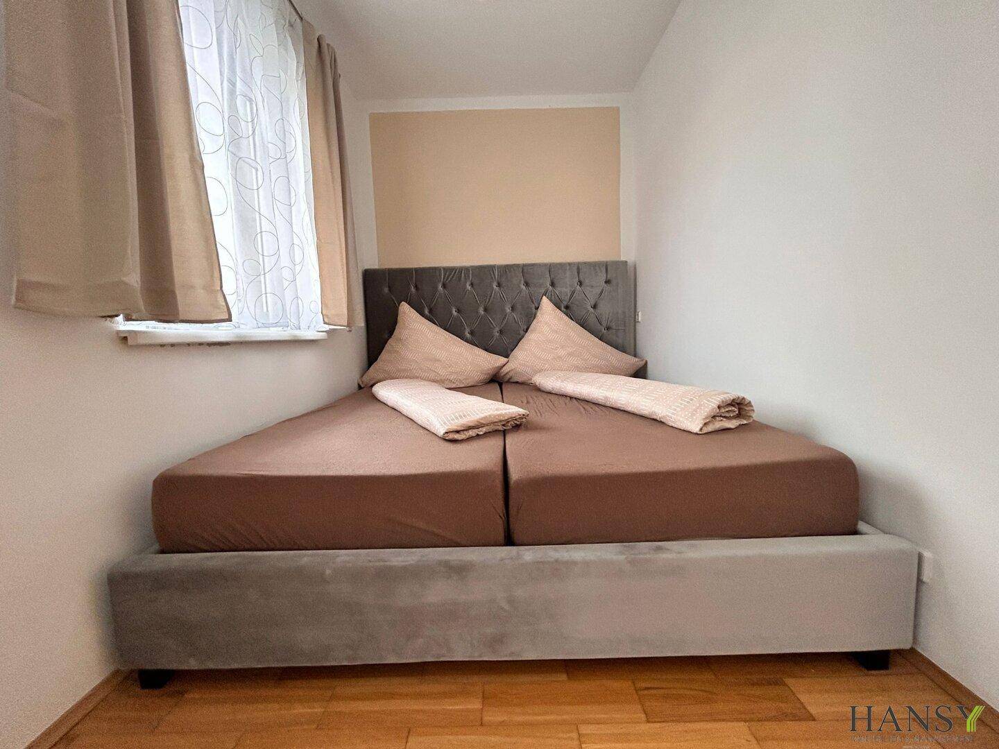 Schlafzimmer mit zwei Einzelbetten, die zu einem Doppelbett arrangiert sind, und Holzboden.
