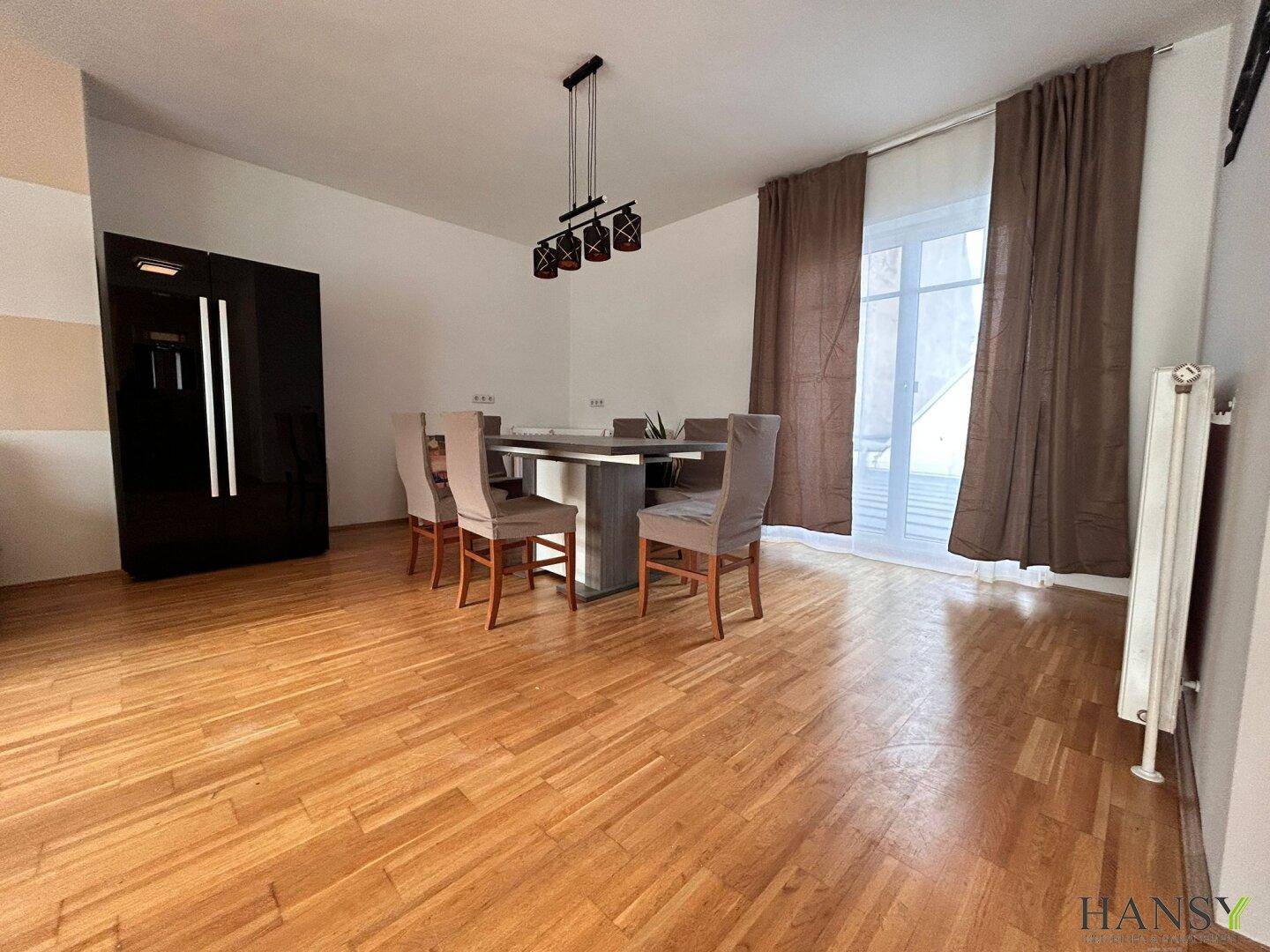 Essbereich mit modernem Esstisch und Stühlen, ergänzt durch einen dunklen Schrank und Holzboden.