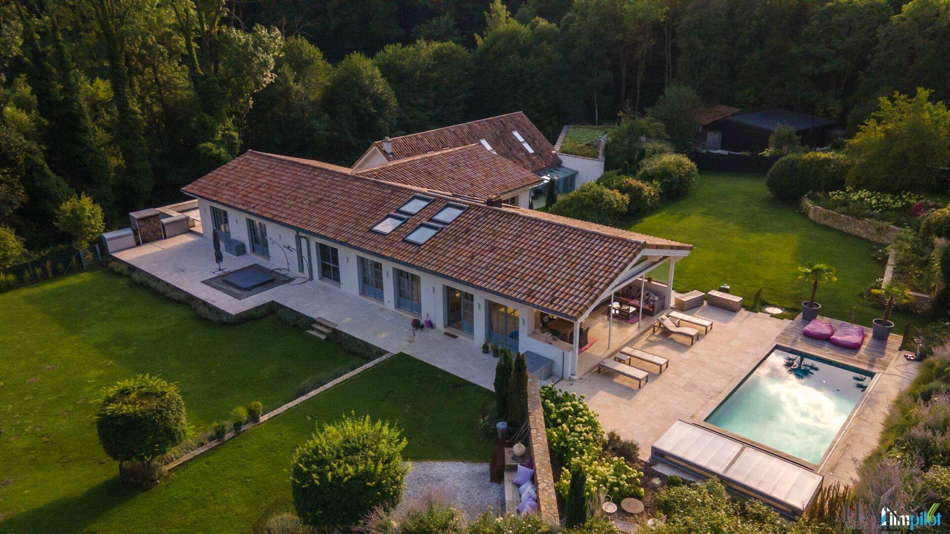 Luxuriöses Anwesen von oben mit großem Pool, weitläufiger Terrasse und gepflegtem Garten in grüner Umgebung.