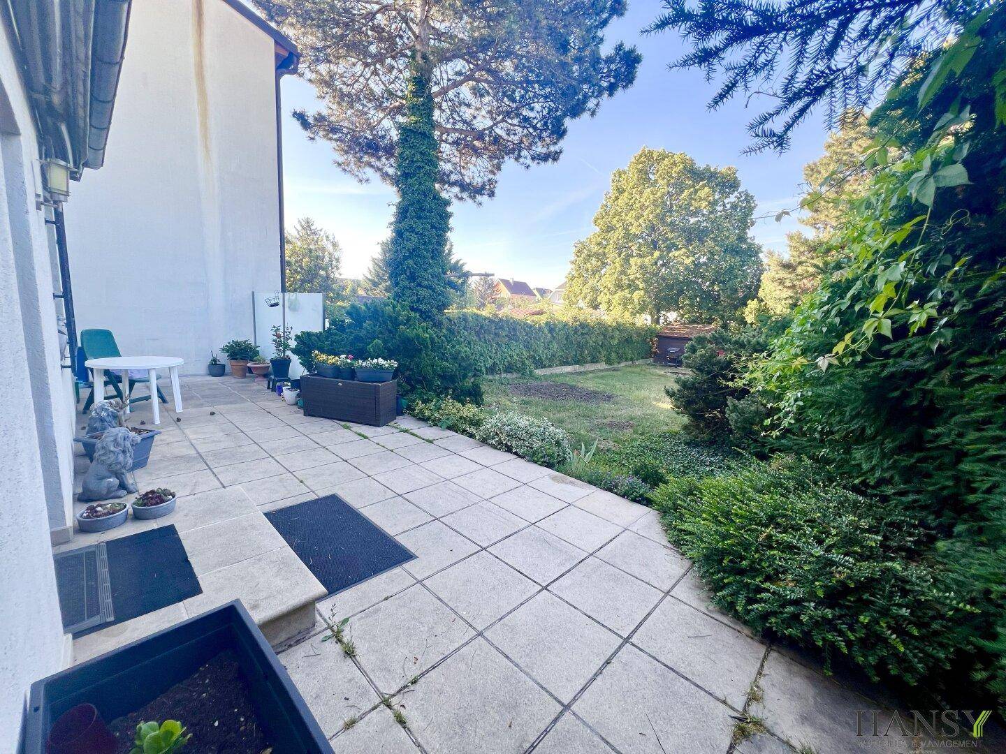 Gemütliche gepflasterte Terrasse mit Gartenmöbeln und Blick ins Grüne.