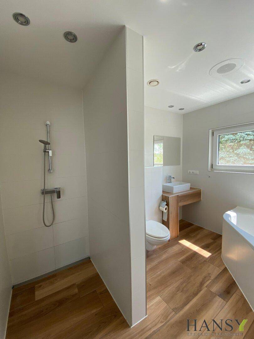 Modernes Badezimmer mit begehbarer Dusche, Einzelwaschbecken und Badewanne.