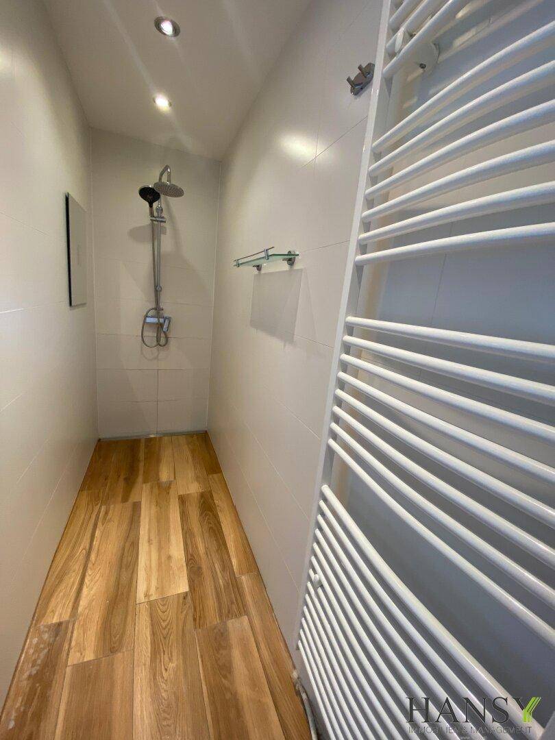 Moderne Duschkabine mit Regendusche und beheiztem Handtuchhalter, Holzoptik-Fliesenboden.