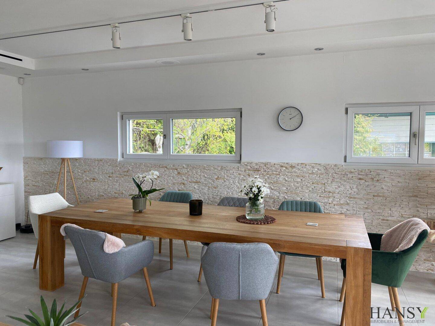 Heller Essbereich mit Holztisch, modernen Stühlen und einer dekorativen Steinwand.