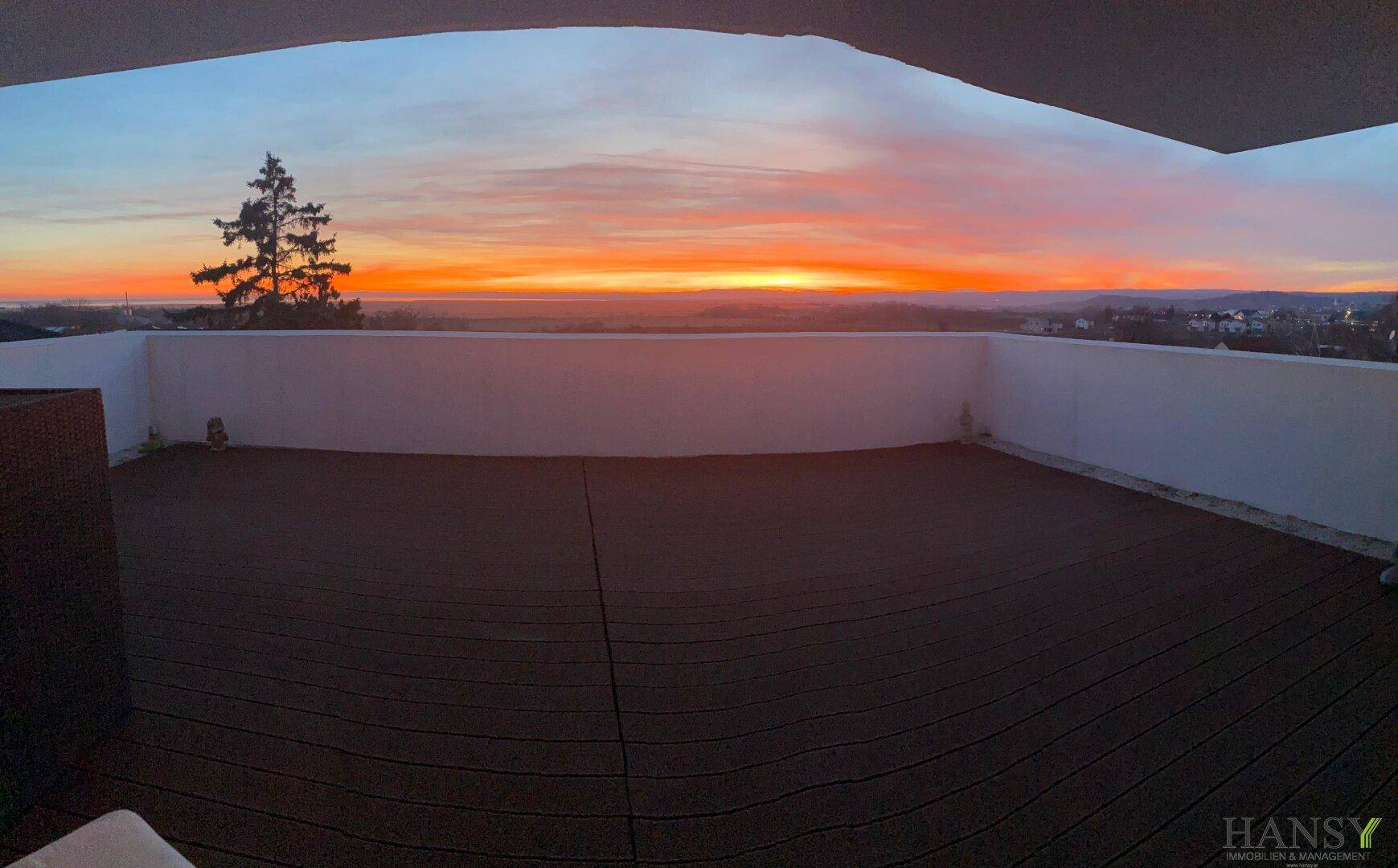 Weitläufige Holzterrasse mit Panoramablick auf den Sonnenuntergang über der weiten Landschaft.