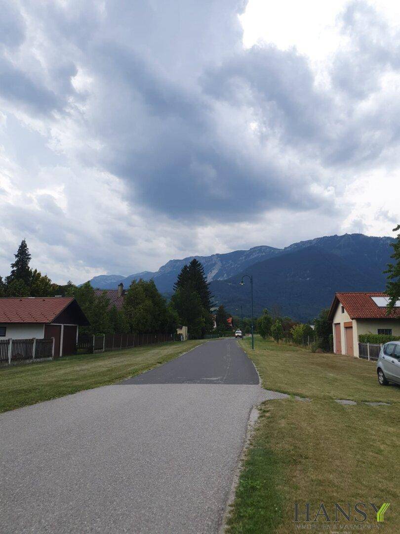 Ländliche Straße mit Blick auf die umliegende Berglandschaft unter einem bewölkten Himmel.