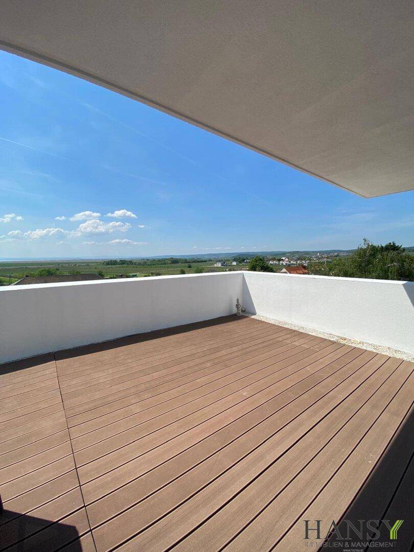 Weitläufige Holzterrasse mit weißer Brüstung und beeindruckendem Panoramablick über die weite Landschaft.