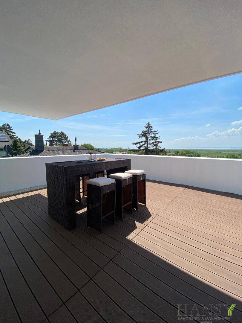 Geräumige Terrasse mit Holzdielen und Esstisch, bietet einen weiten Blick über die malerische Landschaft.