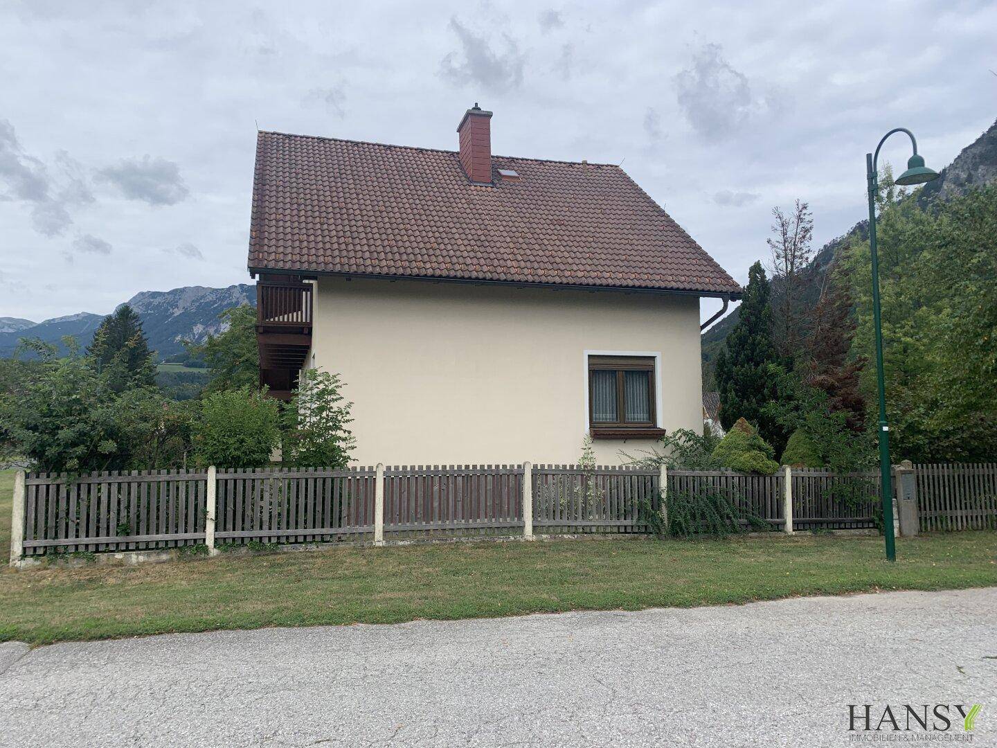 Rückseite des Hauses mit Balkon und Blick auf die umliegende Natur und die Berge.