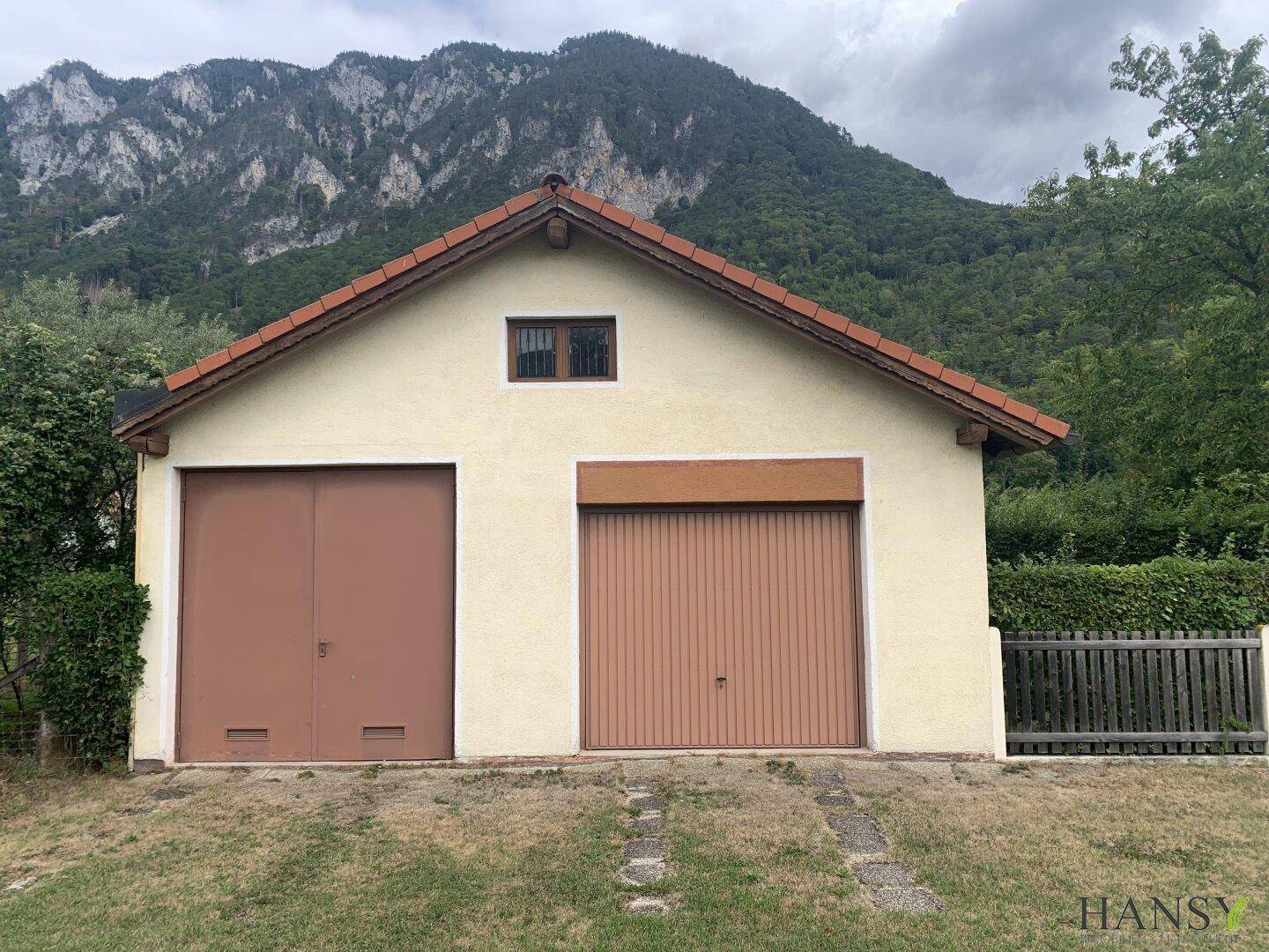Freistehende Doppelgarage mit zwei Toren und Satteldach in ländlicher Umgebung.