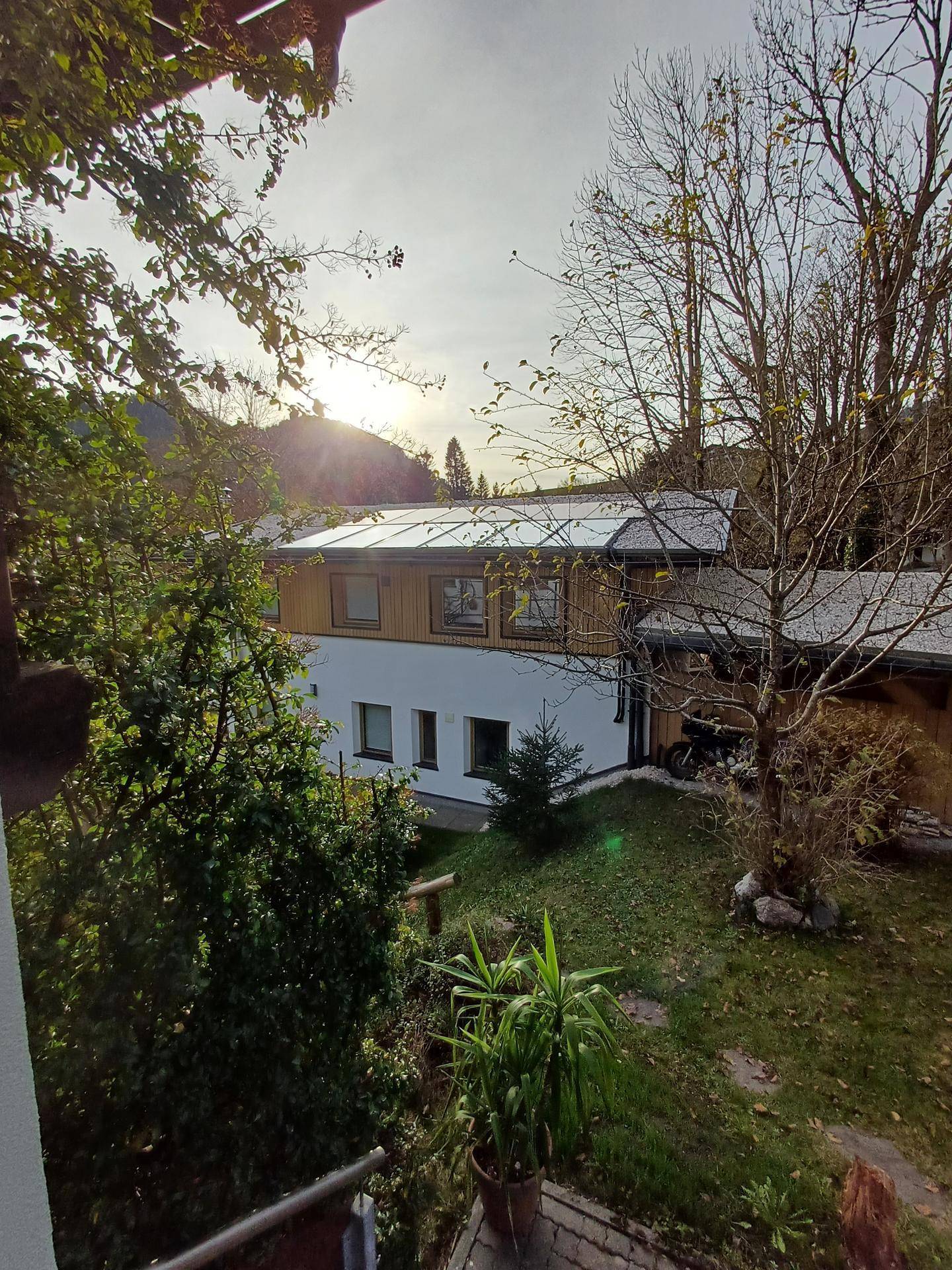Ansicht des Hauses von oben mit Solarpaneelen auf dem Dach und umgebender Natur.