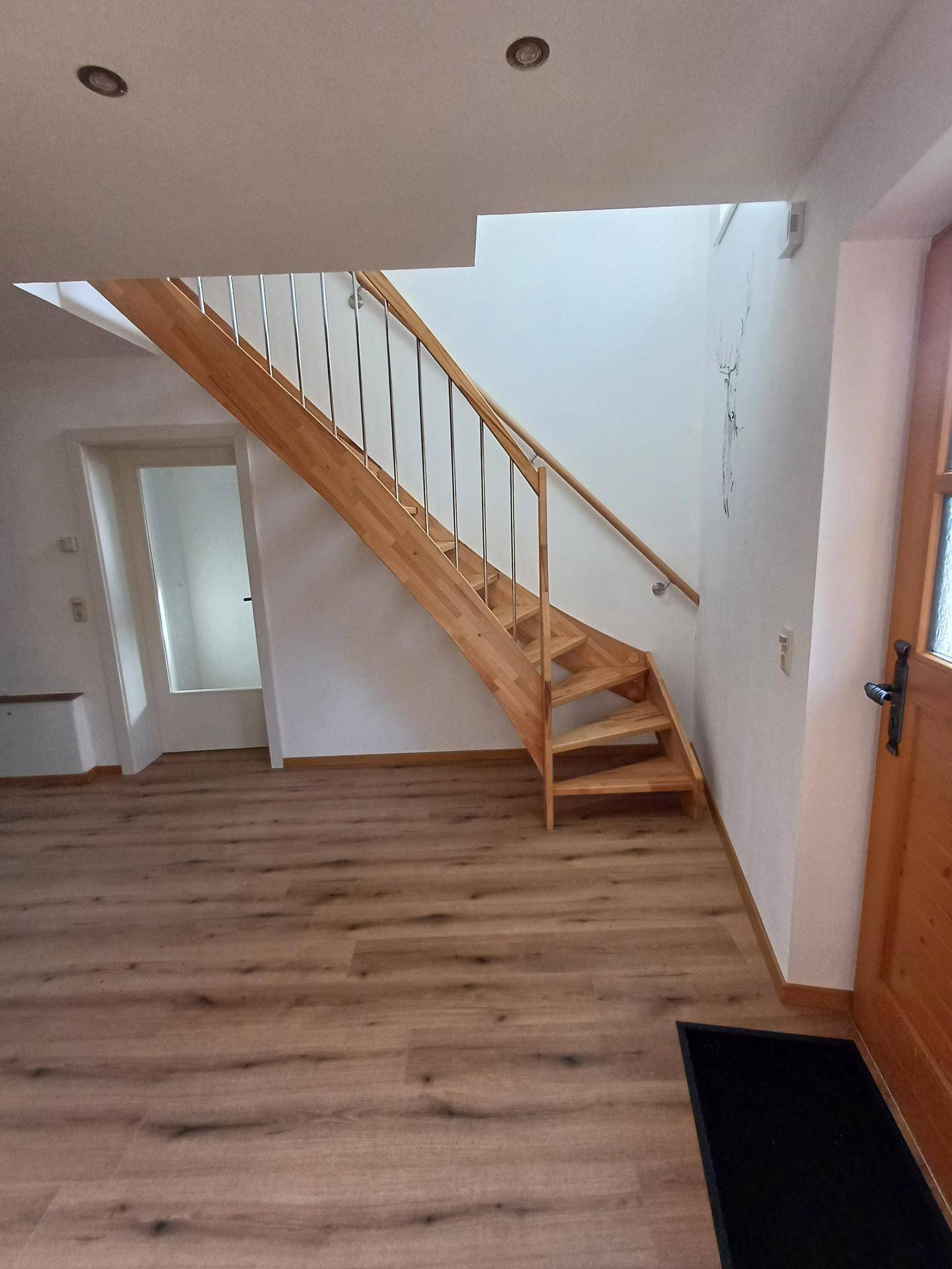 Helle Holztreppe mit modernen Metallgeländern führt in die obere Etage.