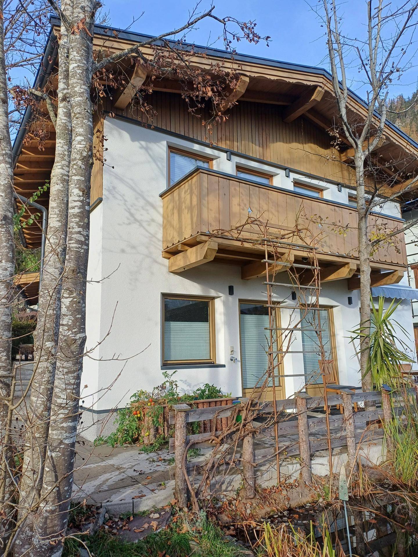 Detailansicht der Hausfassade mit Holzelementen und einem kleinen Balkon im alpinen Stil.