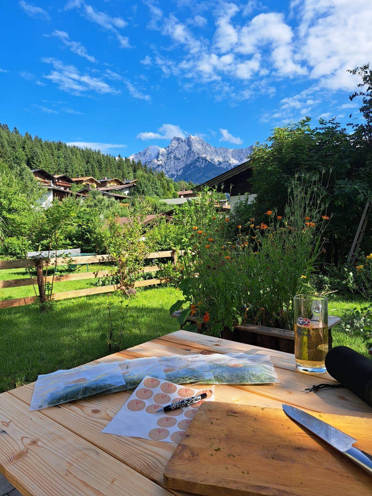 Holztisch im Garten mit Bergblick, vorbereitet für die Zubereitung von Speisen.