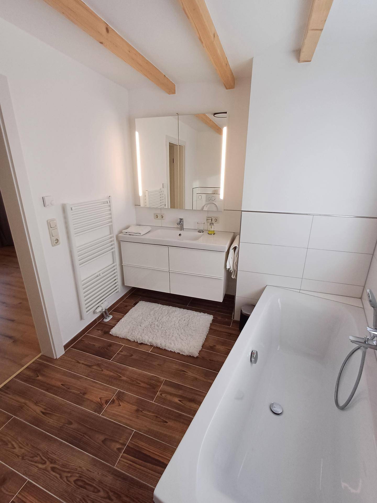 Badezimmer mit modernem Waschtisch, Spiegelschrank und beheiztem Handtuchhalter.