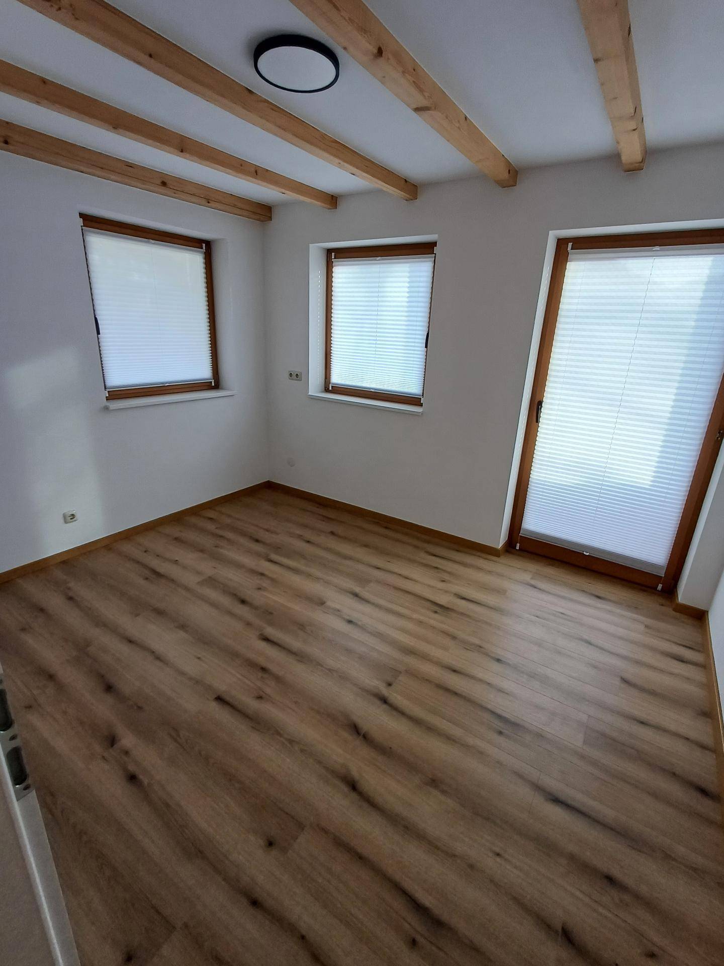 Schlafzimmer mit mehreren Fenstern und Zugang zu einem Außenbereich, hell und freundlich.