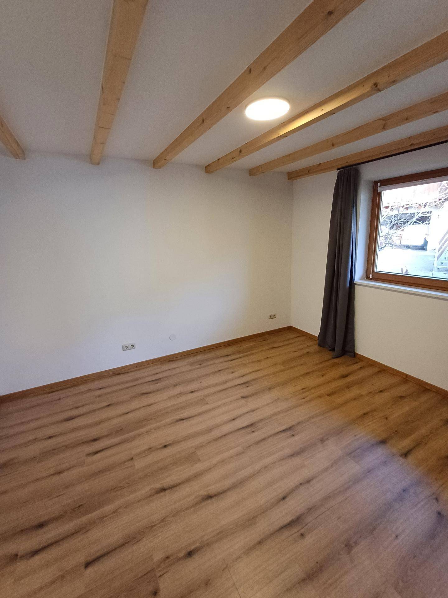 Geräumiger Raum mit Laminatboden und einem Fenster, bereit zur individuellen Gestaltung.