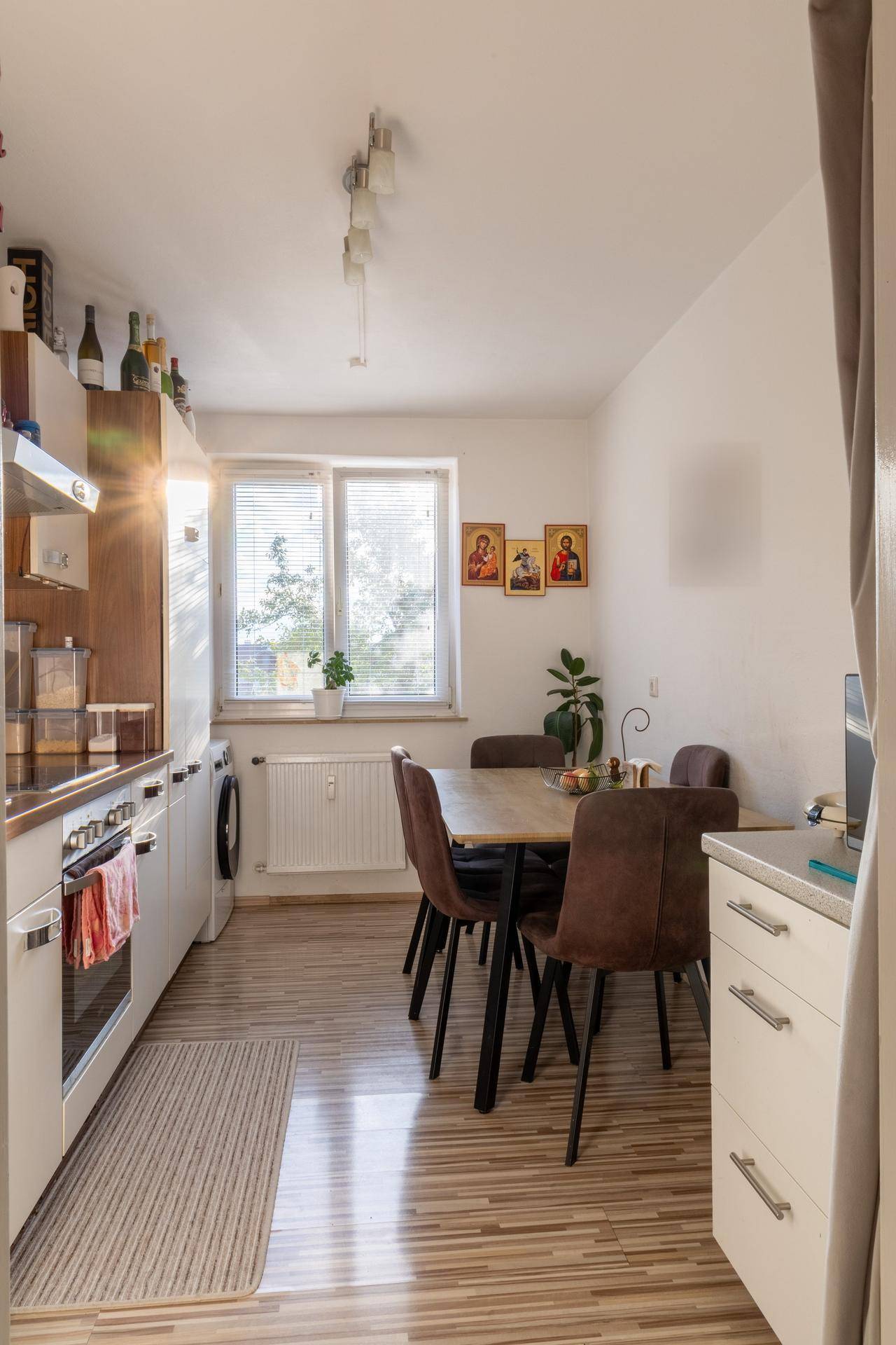Funktionale Küche mit Essbereich, Holzschränken, Fenster und Laminatboden.