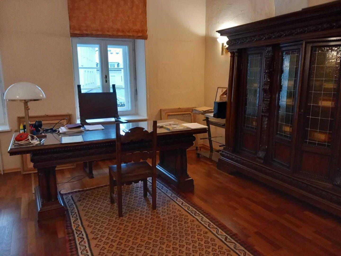 Detailansicht eines großen, antiken Holzschreibtisches und eines passenden Schranks in einem Büro.