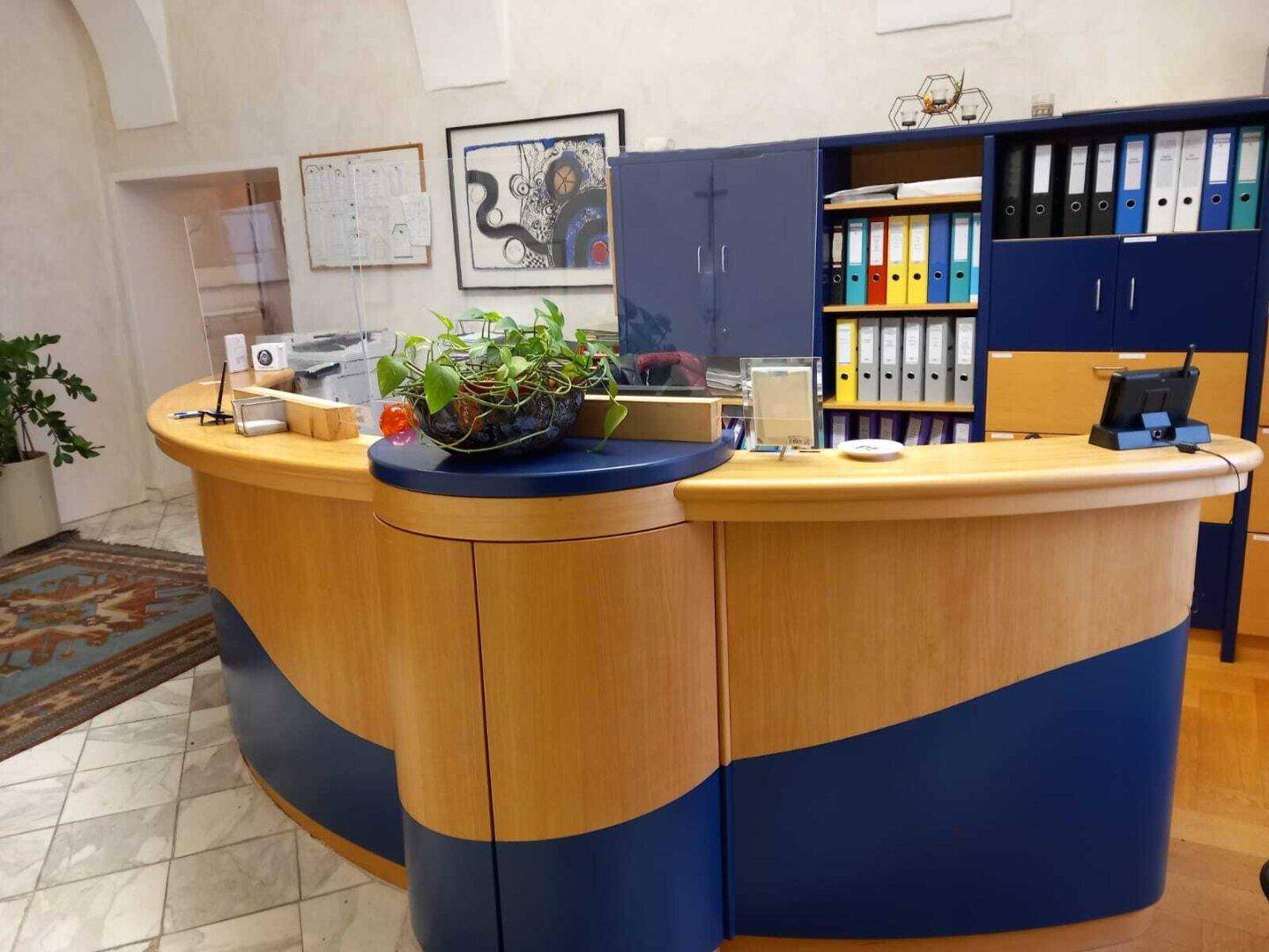 Moderne Rezeptionstheke mit blauen Akzenten und dahinterliegenden Büroschränken.