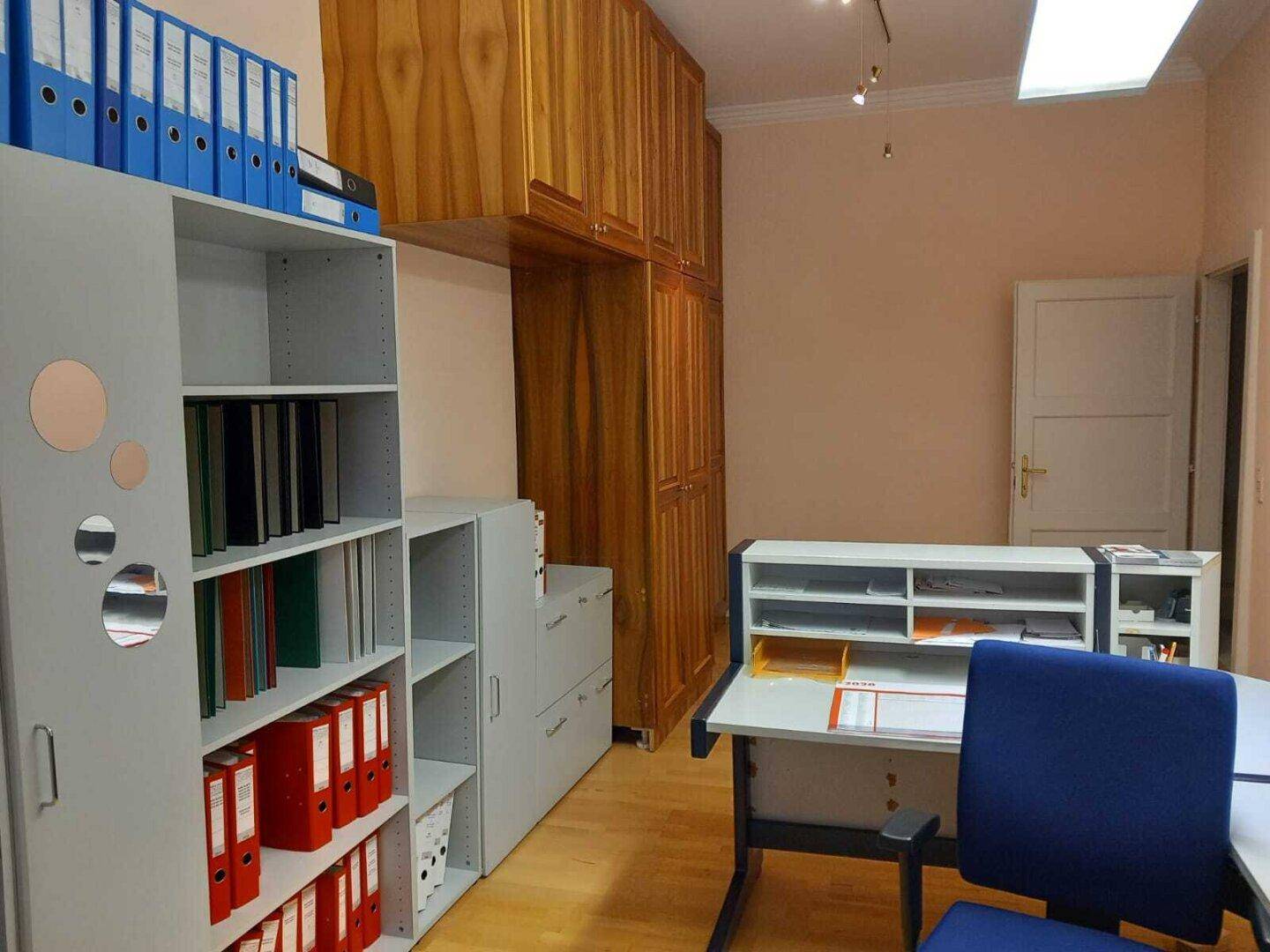 Büro mit Holzboden, Regalen voller Aktenordner und einem modernen Schreibtisch.