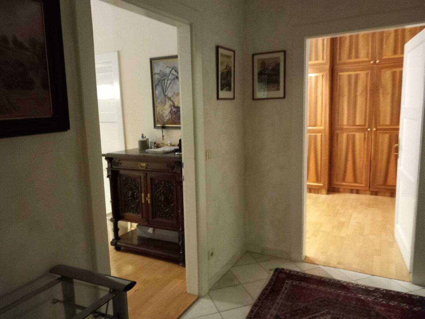 Flur mit Fliesenboden und Zugang zu zwei angrenzenden Räumen mit Holzboden.