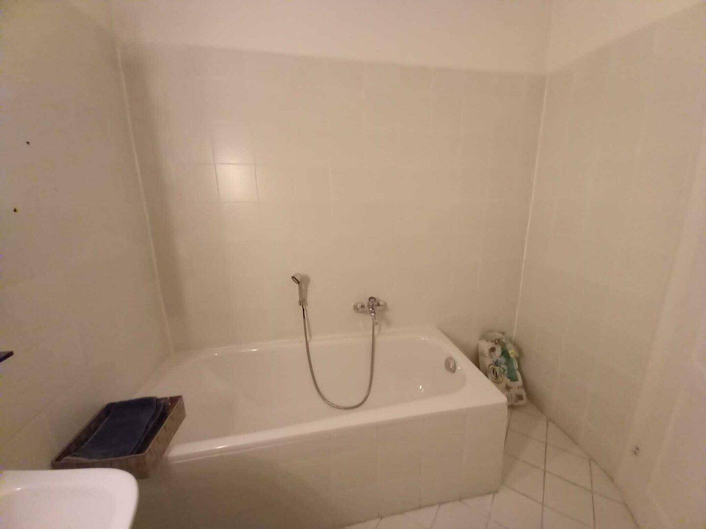Badezimmer mit weißer Badewanne und Fliesenboden, bereit für die Nutzung.