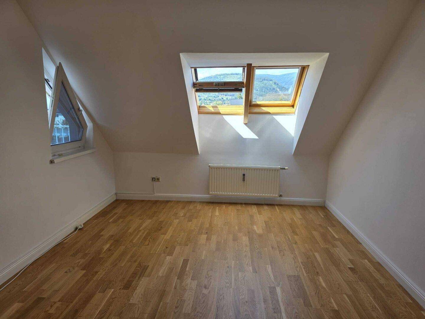 Gemütliches Schlafzimmer im Dachgeschoss mit Holzboden und Dachfenstern für viel Licht.