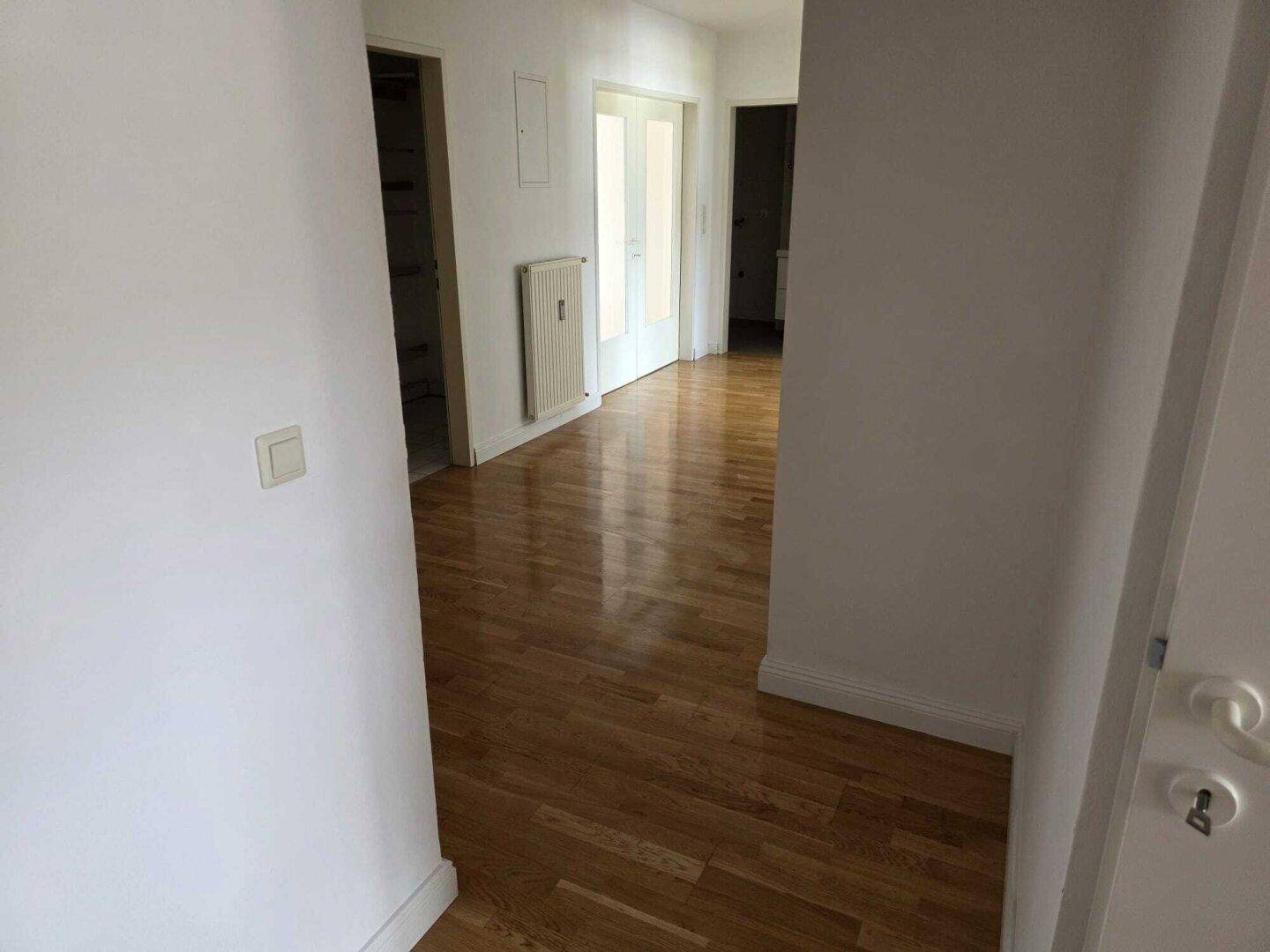 Heller Flur mit Holzboden, der zu verschiedenen Räumen der Wohnung führt.