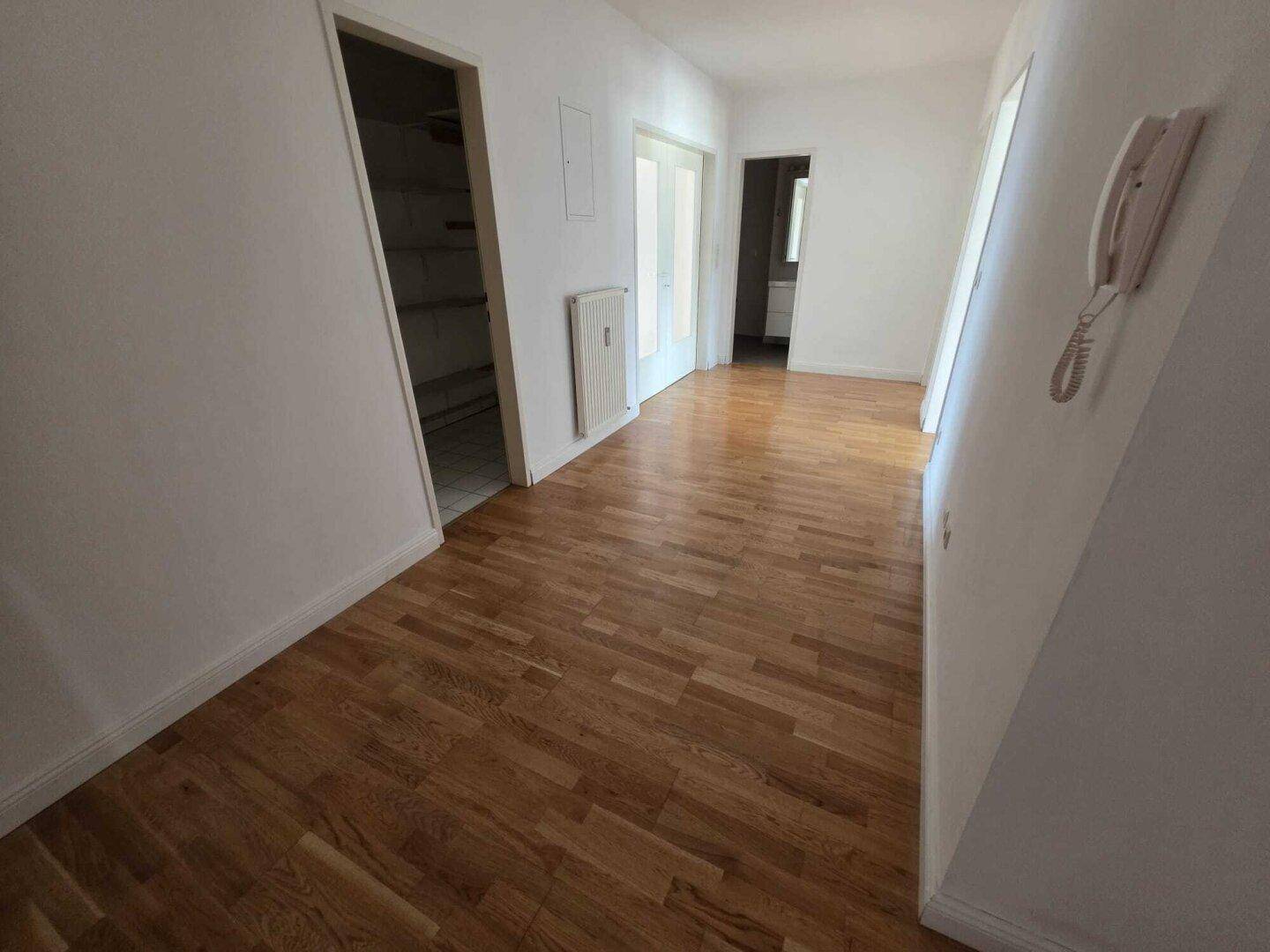 Geräumiger Flur mit glänzendem Holzboden und Zugang zu weiteren Zimmern.