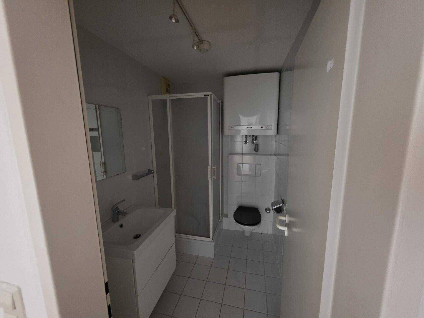 Funktionales Badezimmer mit Dusche, WC und Waschbecken in hellen Fliesen.