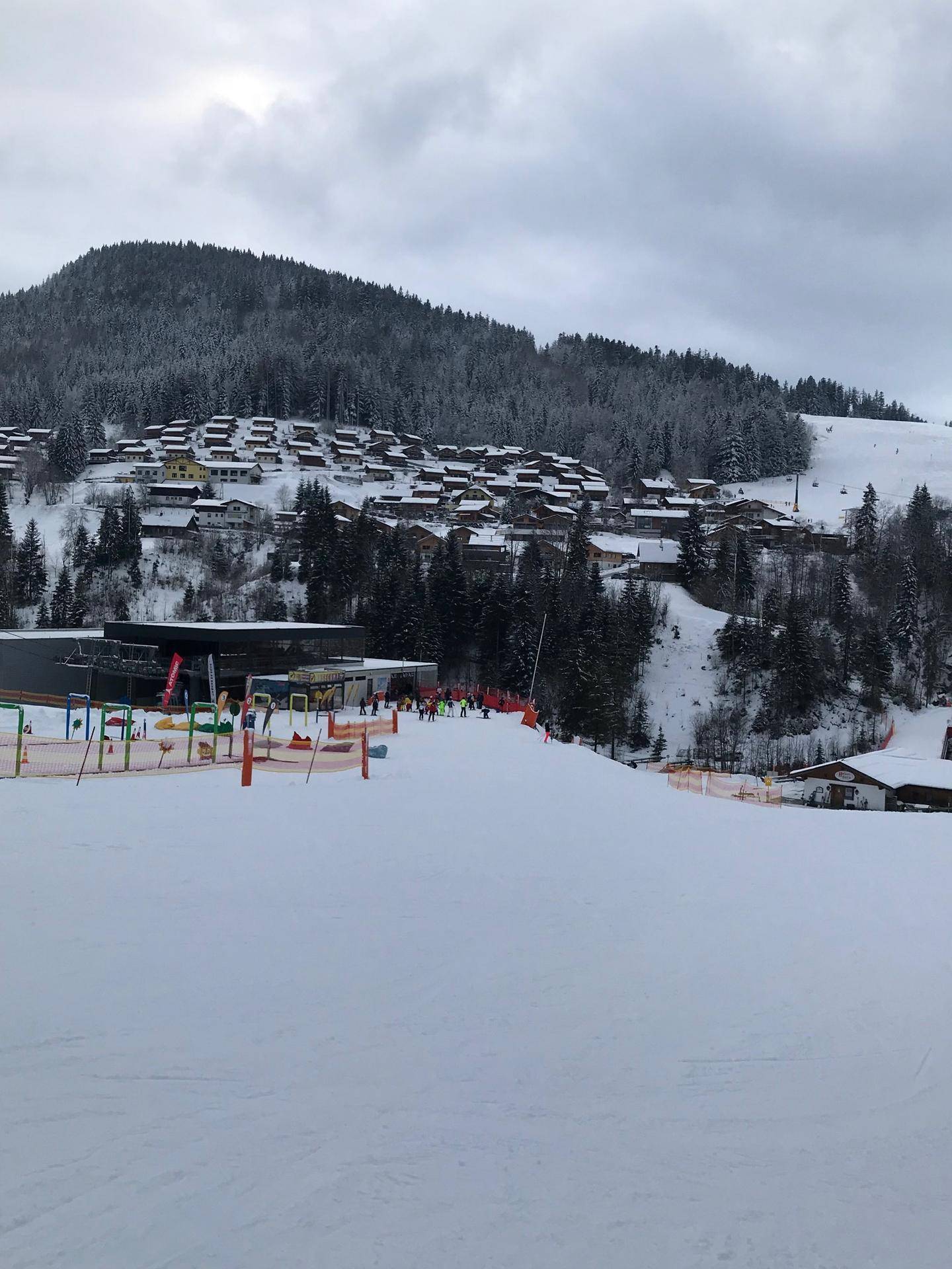 Winterlandschaft mit einem Skigebiet, vielen Häusern und verschneiten Pisten.