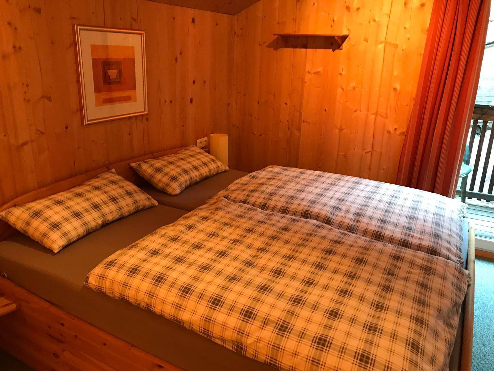 Helles Schlafzimmer mit Holzvertäfelung und karierter Bettwäsche in gemütlicher Atmosphäre.